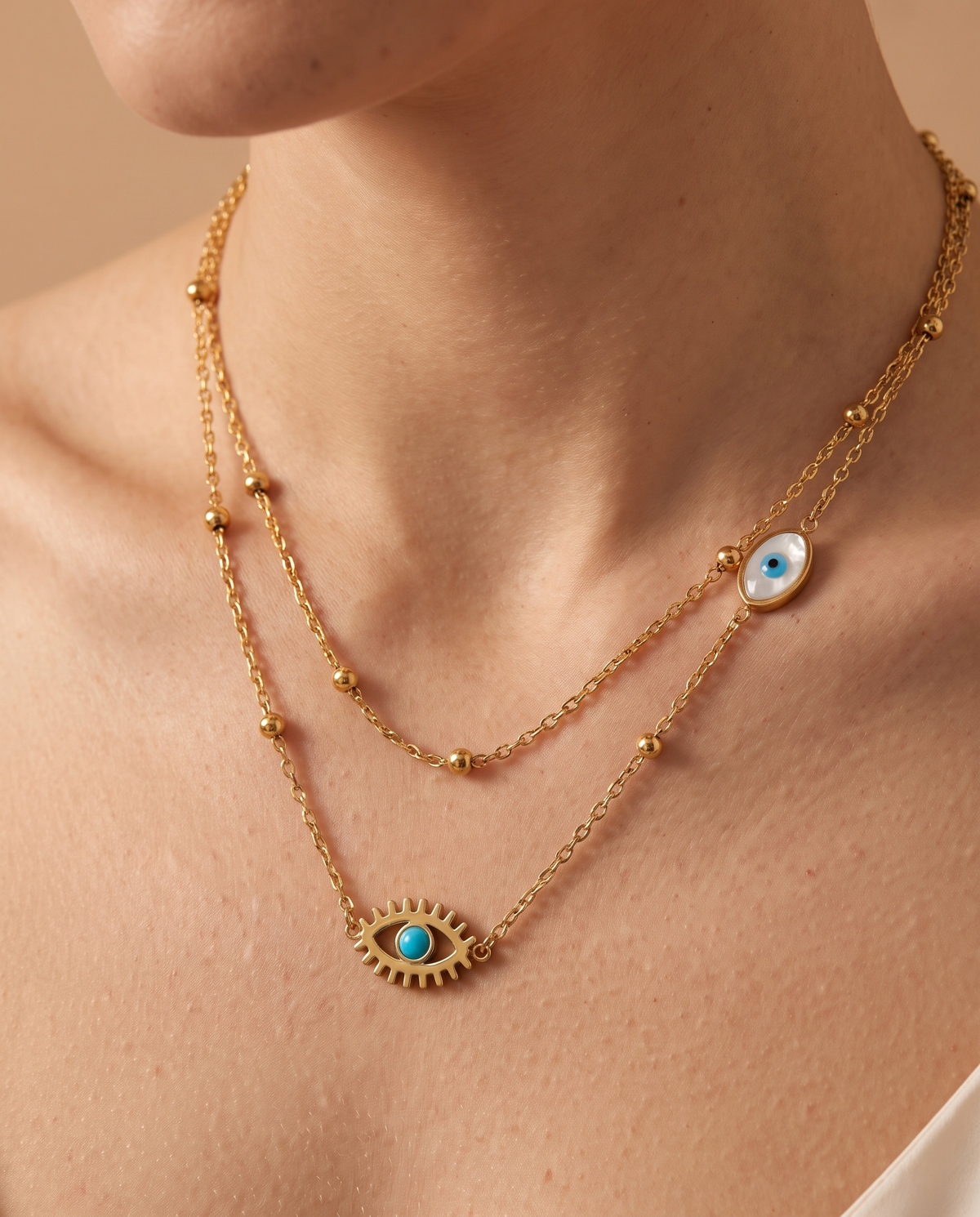 Eternal Flame Necklace, close-up of evil eye charm and gold-tone beads | Eternal Flame ketting, close-up van boze-oog bedel en goudkleurige kraaltjes