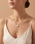 Sweet Glow Necklace, double gold-tone chain with discs and mother-of-pearl-look pendants worn on model | Sweet Glow ketting, dubbele goudkleurige ketting met schijfjes en parelmoerkleurige hangers gedragen door model