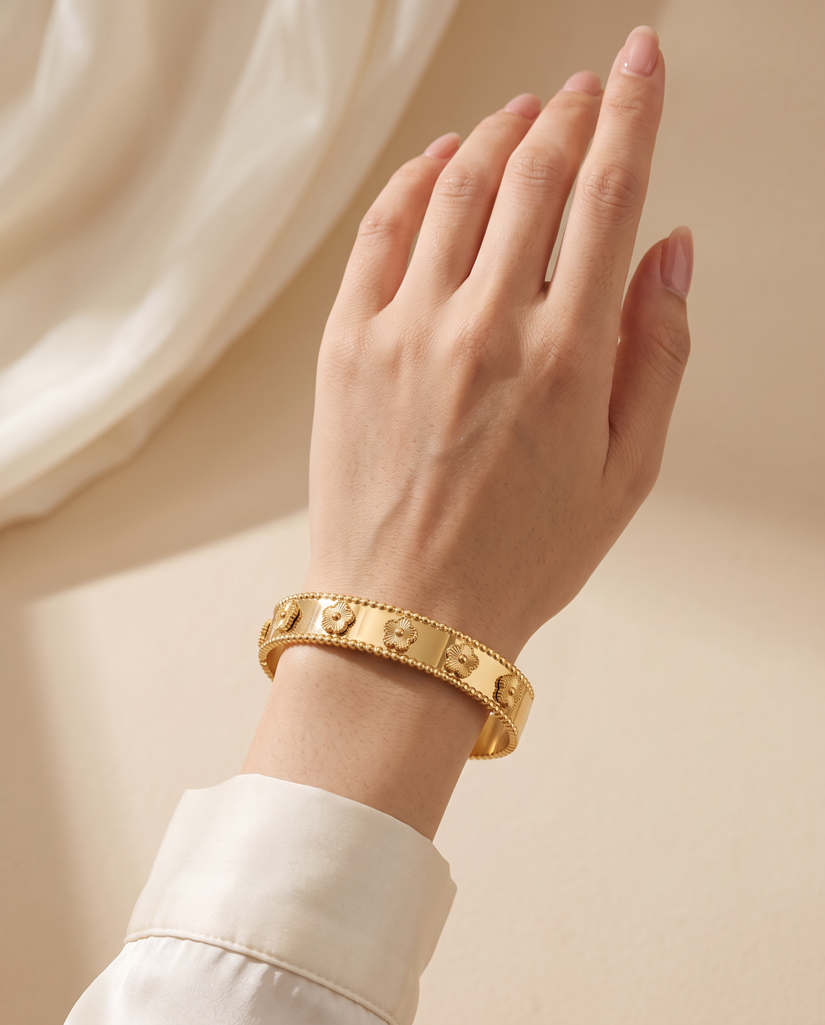 Gentle Shine Bangle worn on the wrist: wide gold-tone bangle with five-petal flowers | Gentle Shine bangle om de pols: brede goudkleurige armband met bloemetjes